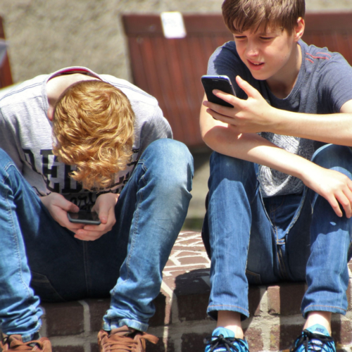 Two teenage boys look at their mobile phones