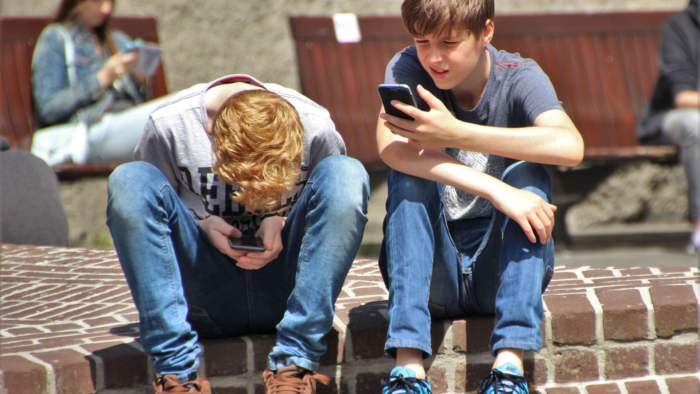 Two teenage boys look at their mobile phones