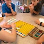 A Montessori teacher explains a maths exercise to students