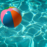A rainbow beachball floating in a blue swimming pool.