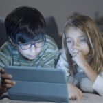 Boy with glasses with girl watgch a screen