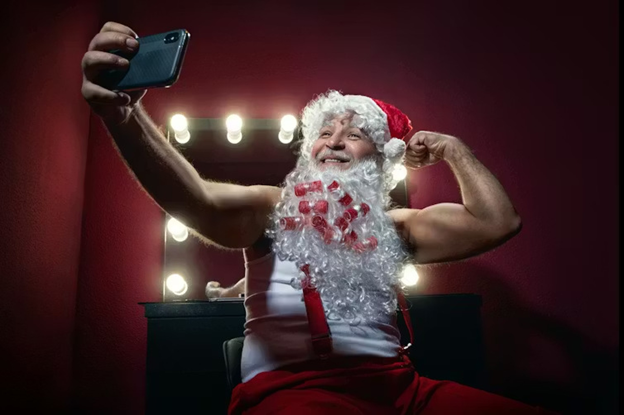 Narcissistic Santa Claus making selfie with mobile camera against the mirror. Wallenrock/Shutterstock